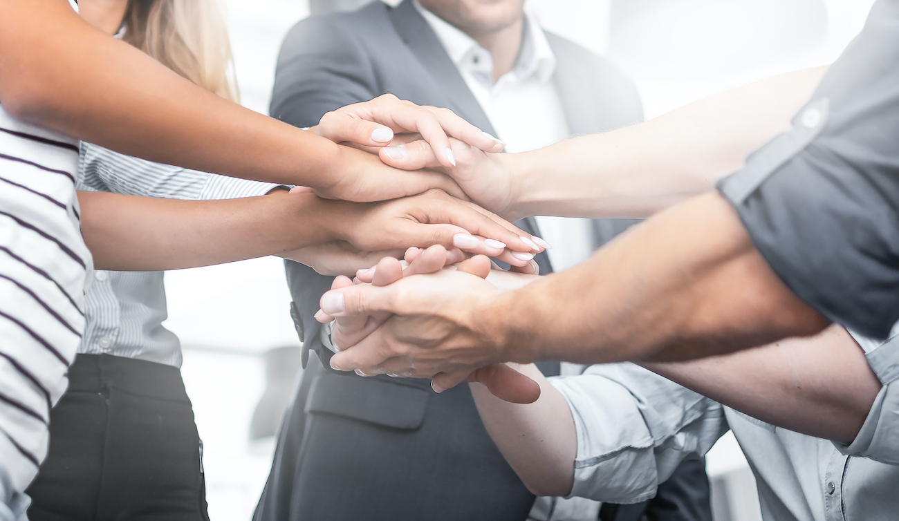 Team putting their hands together to demonstrate they have a culture in which they are close and connected to the work they do